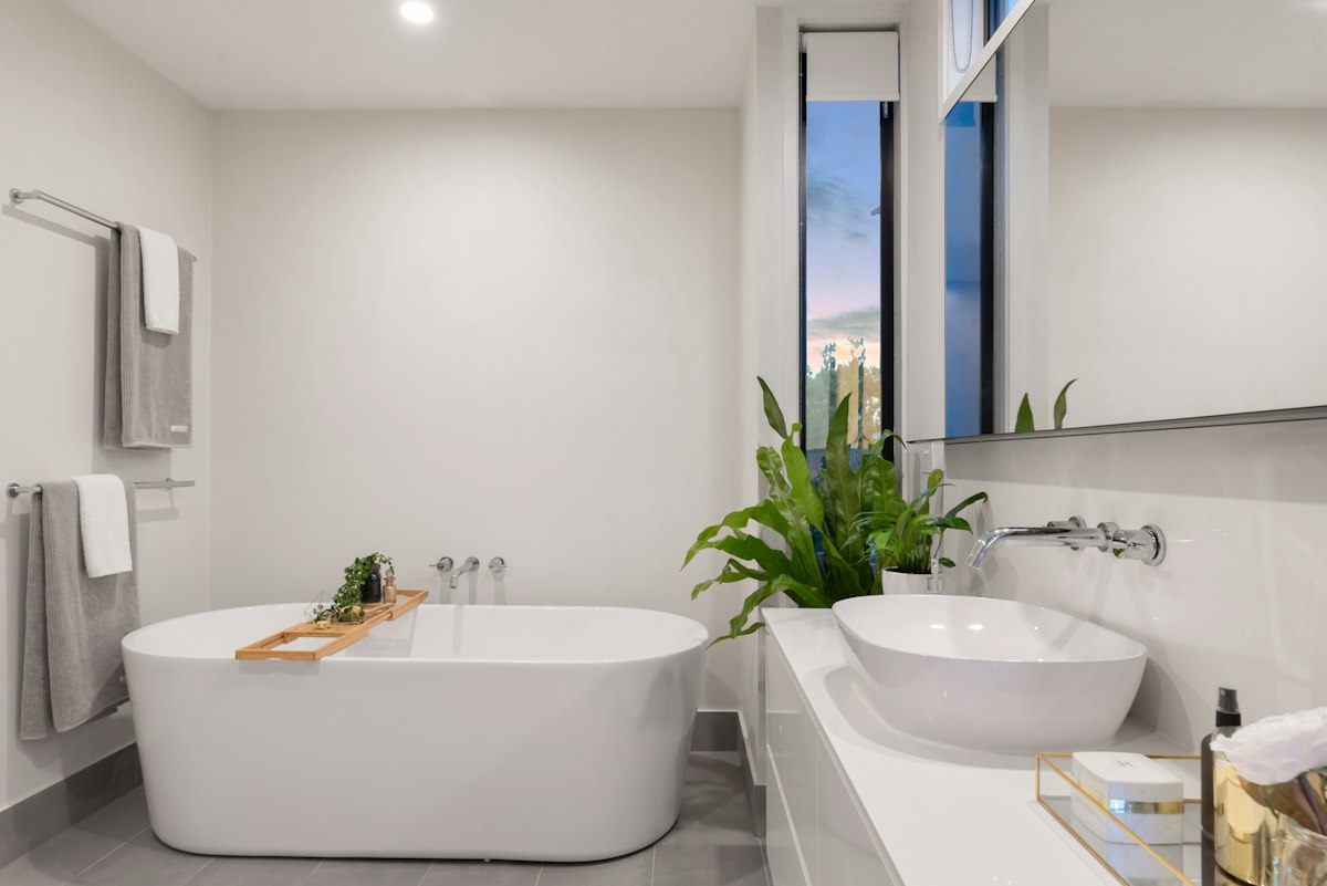 Bagno moderno con vasca freestanding bianca, lavabo d'appoggio e finiture minimal